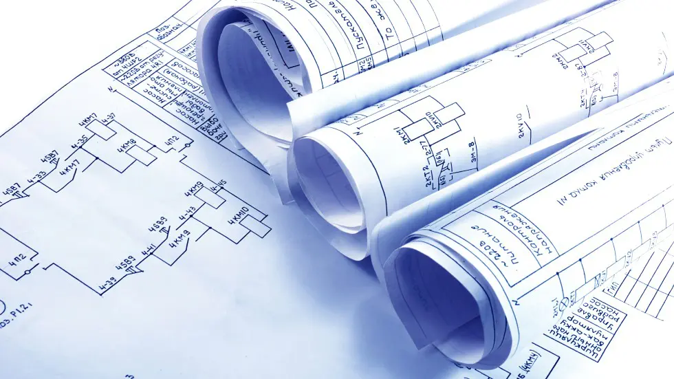 Rolled architectural blueprints on a table showing building plans.